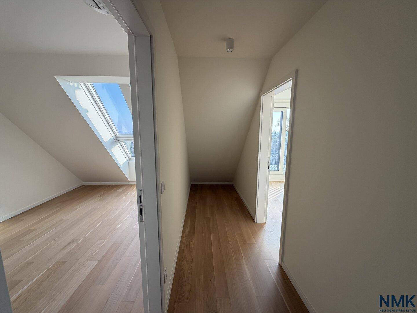 Heller Flur im Dachgeschoss mit Holzboden und Blick in angrenzende Zimmer.