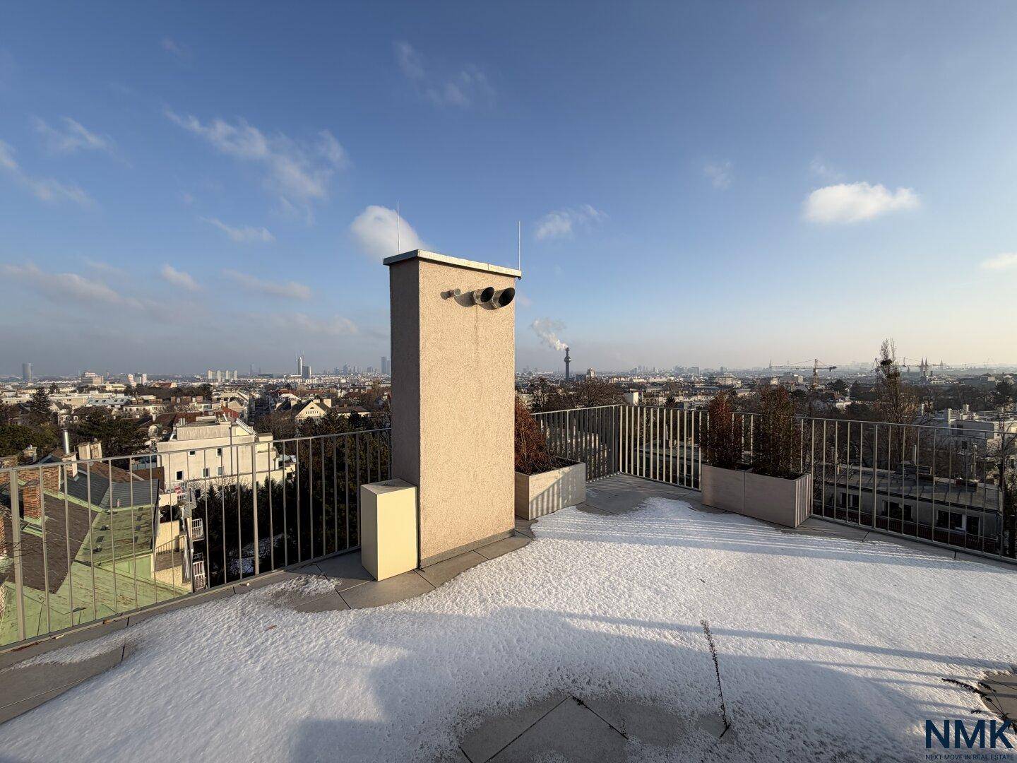 Geräumige Dachterrasse mit Panoramablick über die Stadt, teilweise mit Schnee bedeckt.