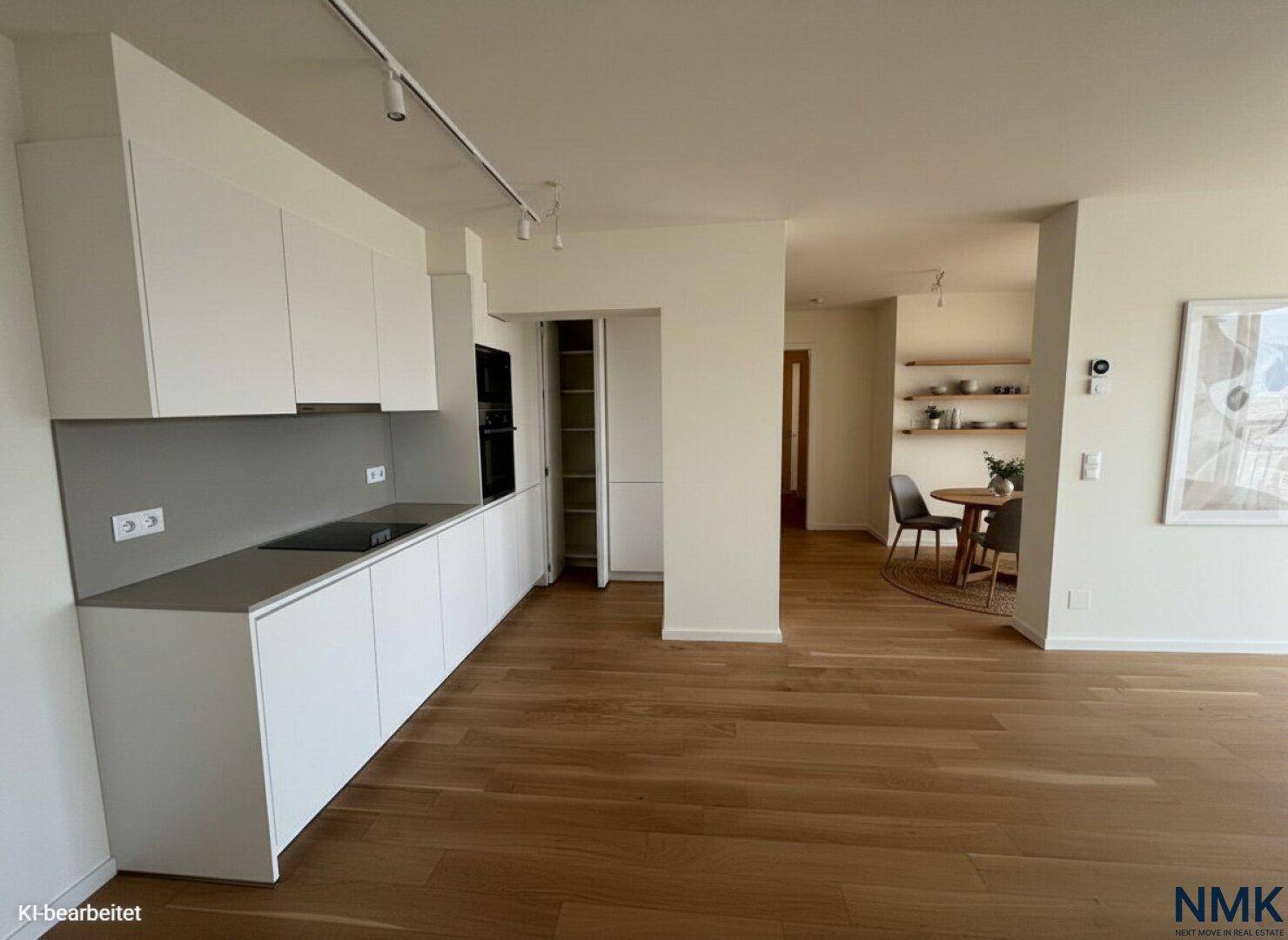 Moderne Einbauküche mit weißen Schränken, Induktionskochfeld und integrierten Geräten in offenem Wohnbereich.