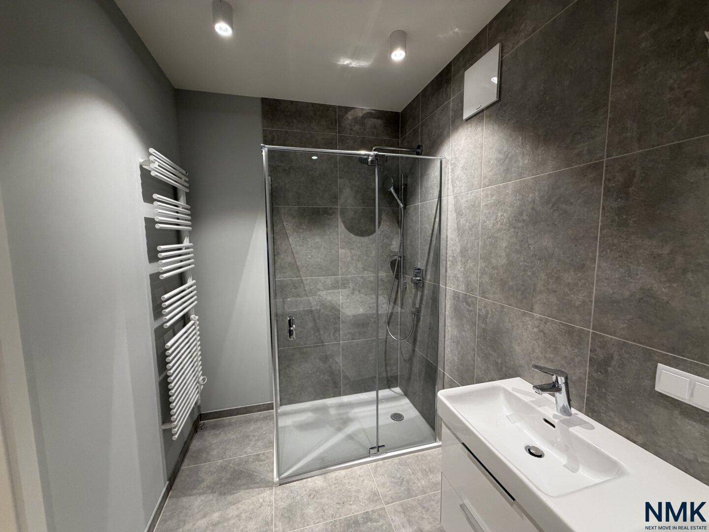 Modernes Badezimmer mit begehbarer Dusche, Waschbecken und beheiztem Handtuchhalter.