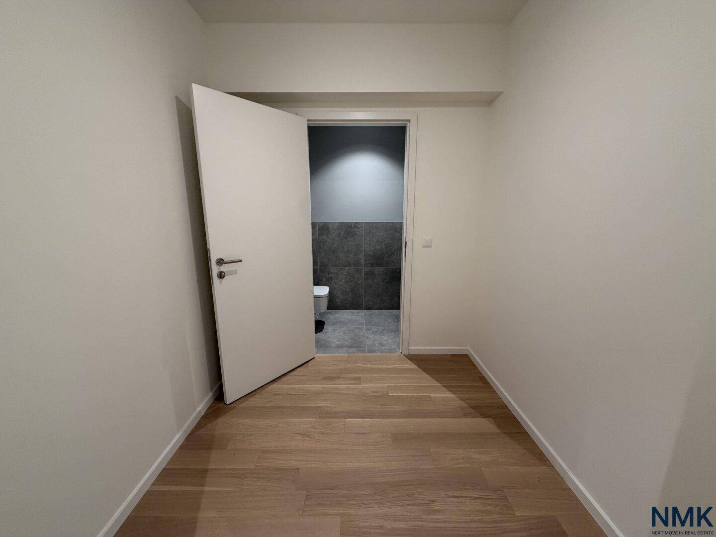 Heller Flur mit Holzboden, der zu einem modernen Gäste-WC führt.