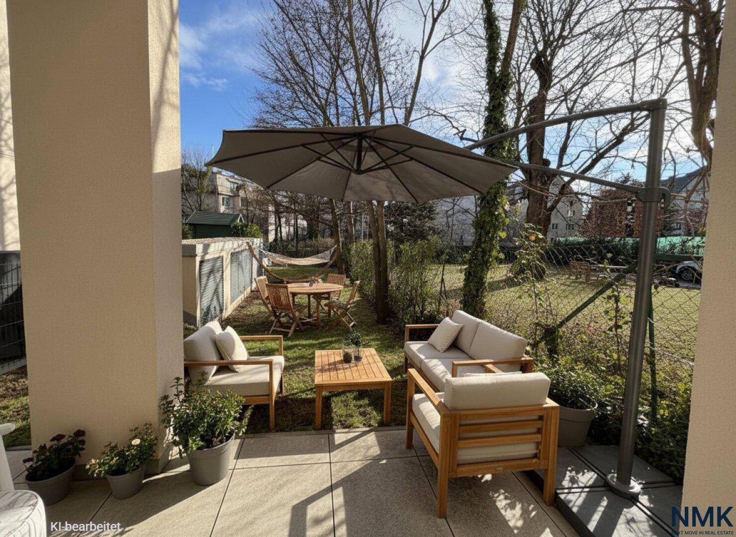 Gemütliche Terrasse mit Gartenmöbeln, Sonnenschirm und Zugang zum grünen Garten.