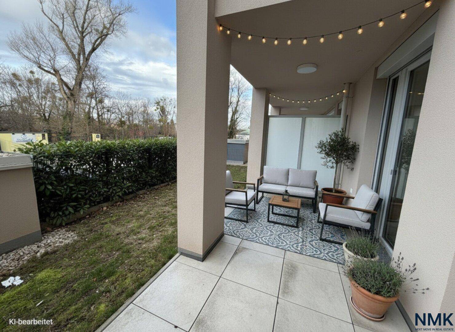 Gemütliche Terrasse mit Outdoor-Möbeln, Lichterkette und Blick auf eine grüne Hecke.