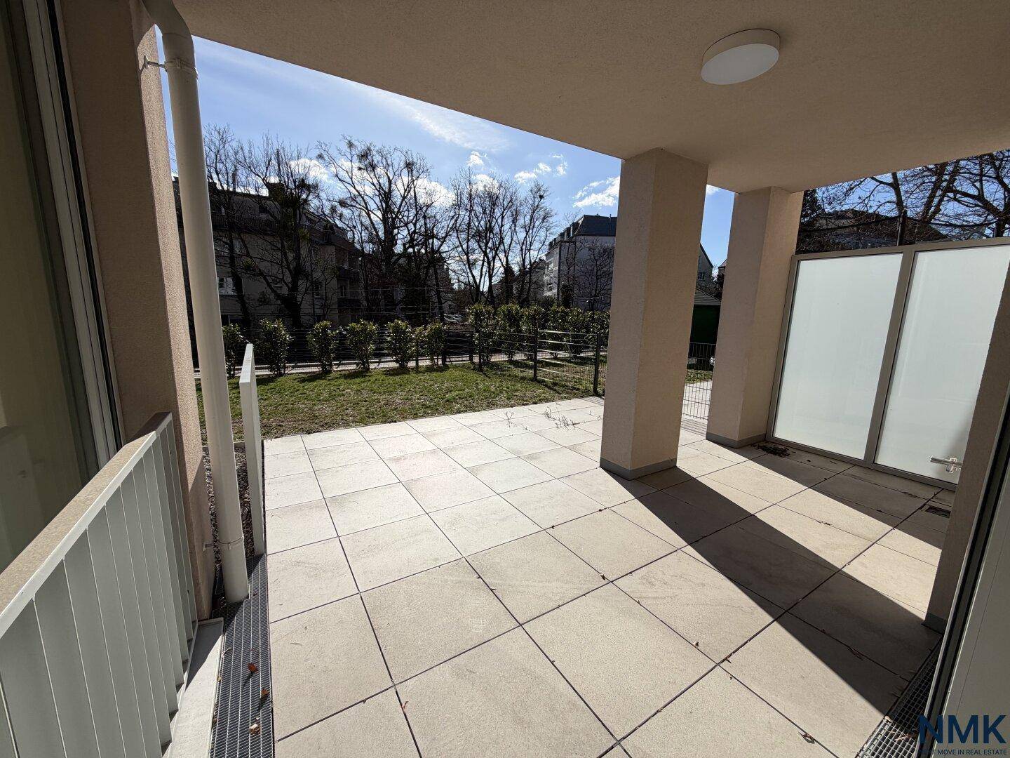 Geräumige, geflieste Terrasse mit Blick auf den Garten und die umliegenden Gebäude.