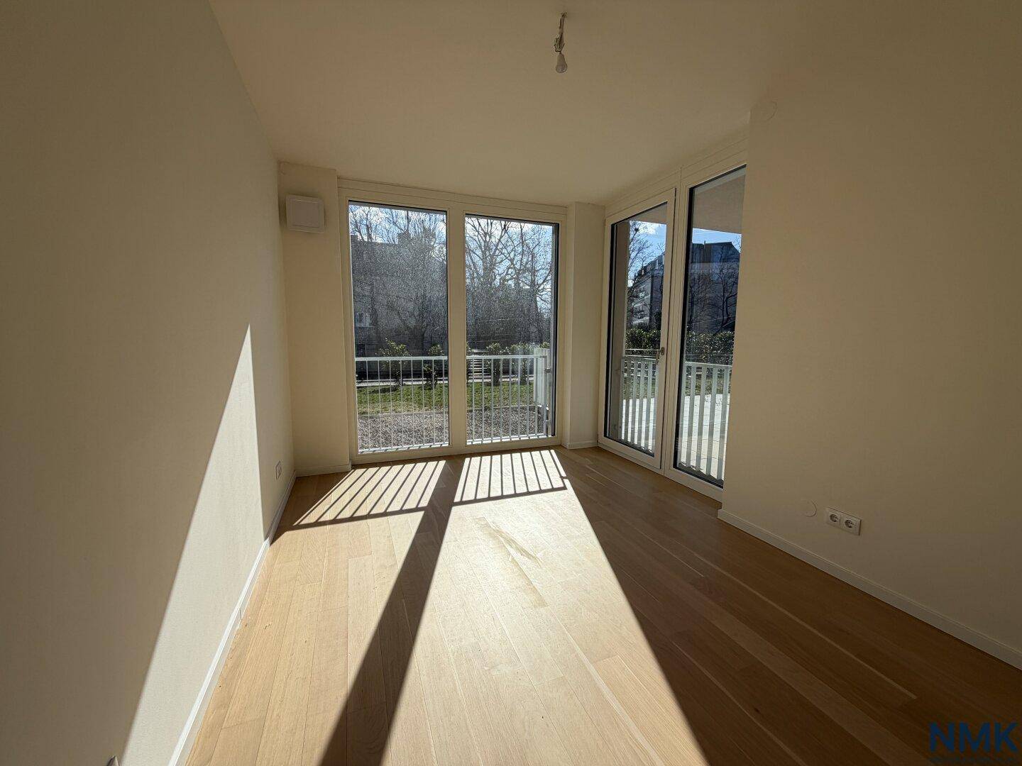Helles Schlafzimmer mit Holzboden und großen Fenstern, die viel Tageslicht hereinlassen.