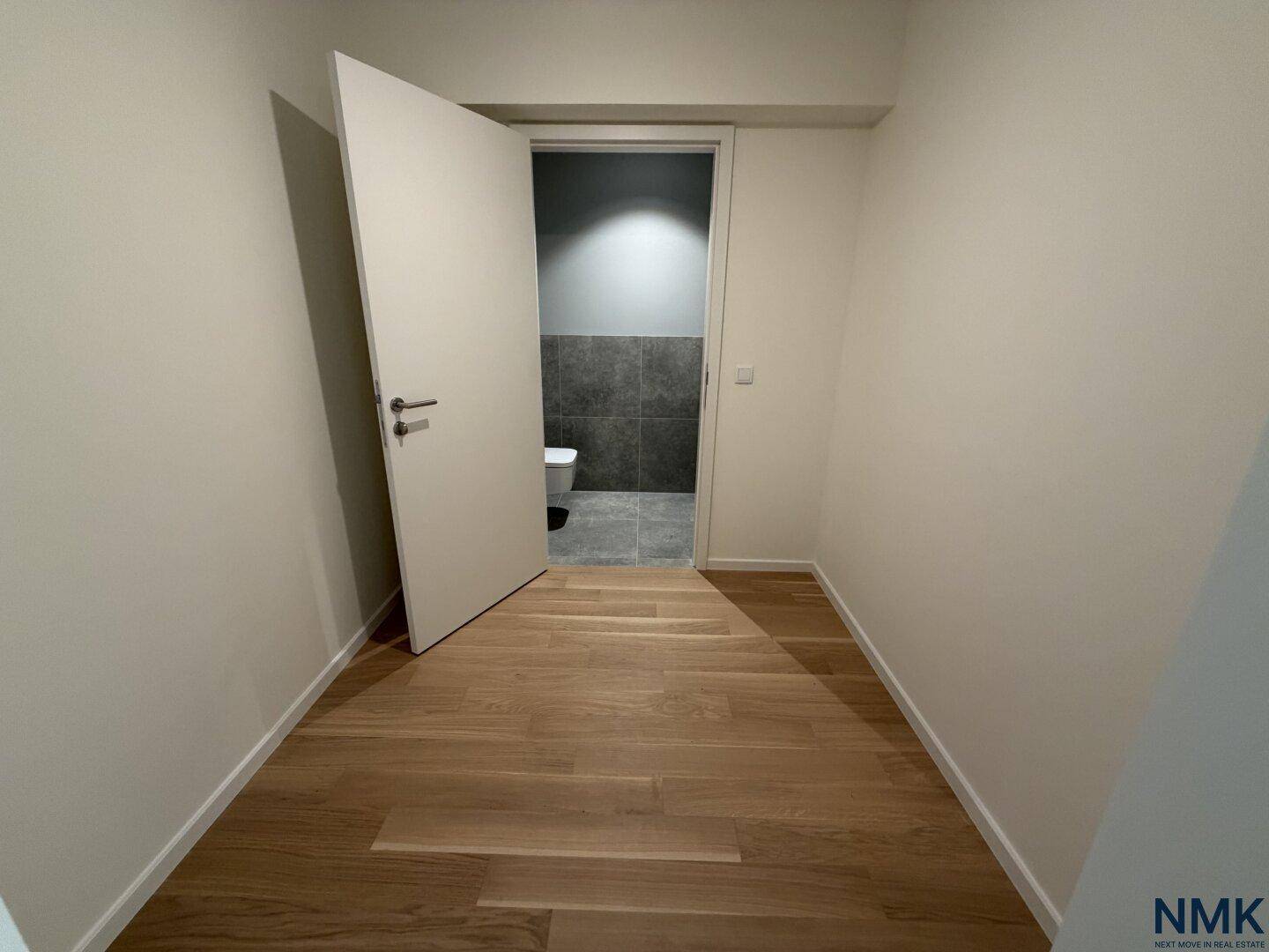 Heller Flur mit Holzboden und Blick auf das Gäste-WC, modern und funktional gestaltet.