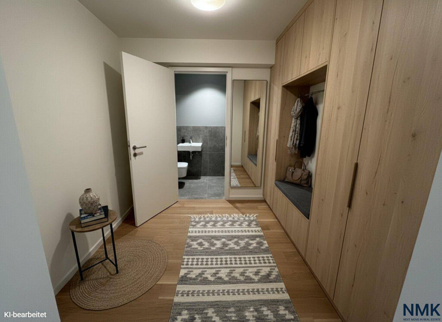 Eingangsbereich mit Holzboden, integrierten Garderobenschränken und Blick auf das Gäste-WC.