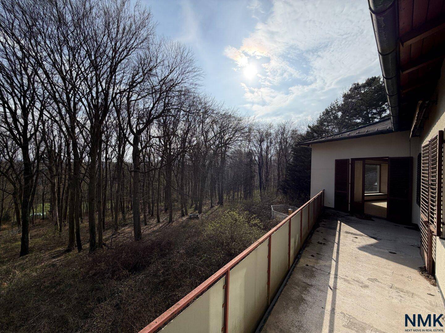 Langer Balkon mit weitem Blick auf den Wald unter strahlendem Sonnenschein.