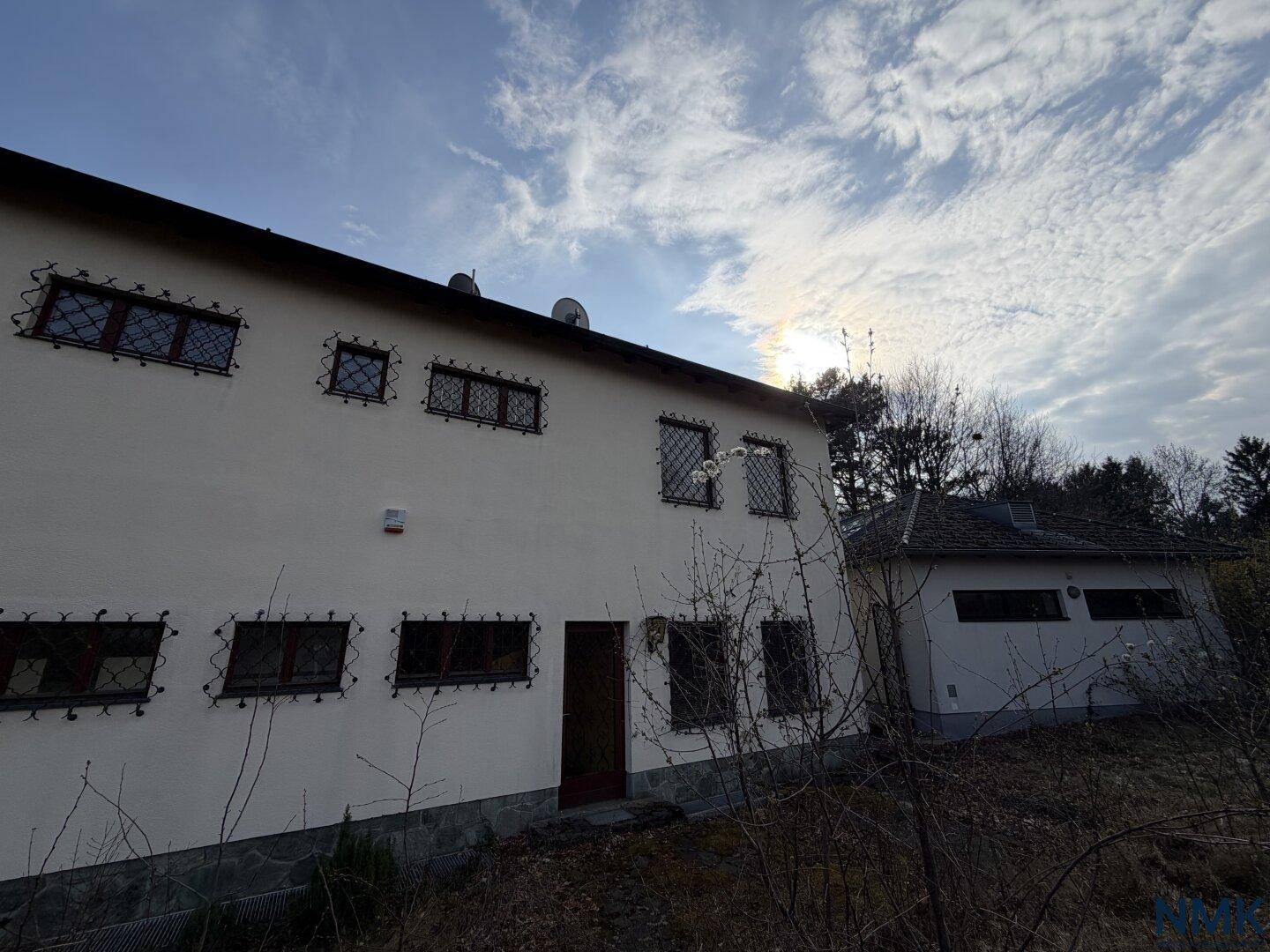 Rückseite des Hauses mit mehreren Fenstern, die mit dekorativen Gittern versehen sind.