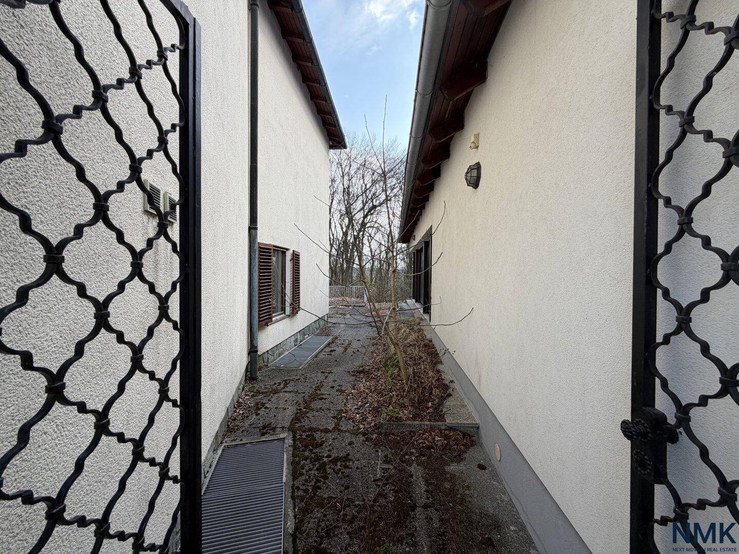 Schmaler Durchgang zwischen dem Haupthaus und dem angrenzenden Nebengebäude.