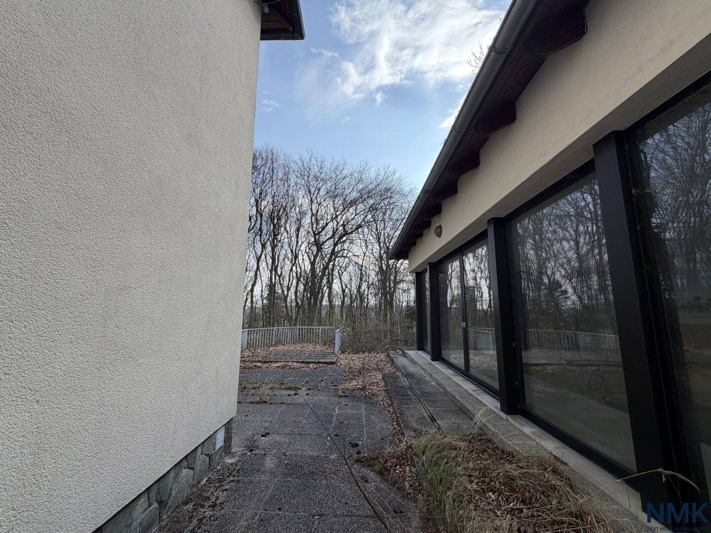 Gepflasterter Bereich neben dem Glasgebäude mit Blick auf die umliegenden Bäume.