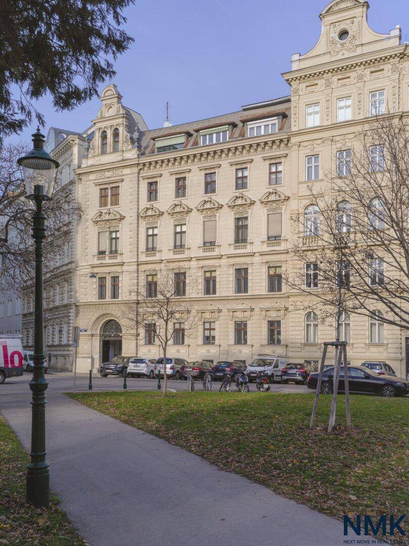 Historisches Gebäude mit aufwendiger Fassade und parkähnlicher Umgebung.
