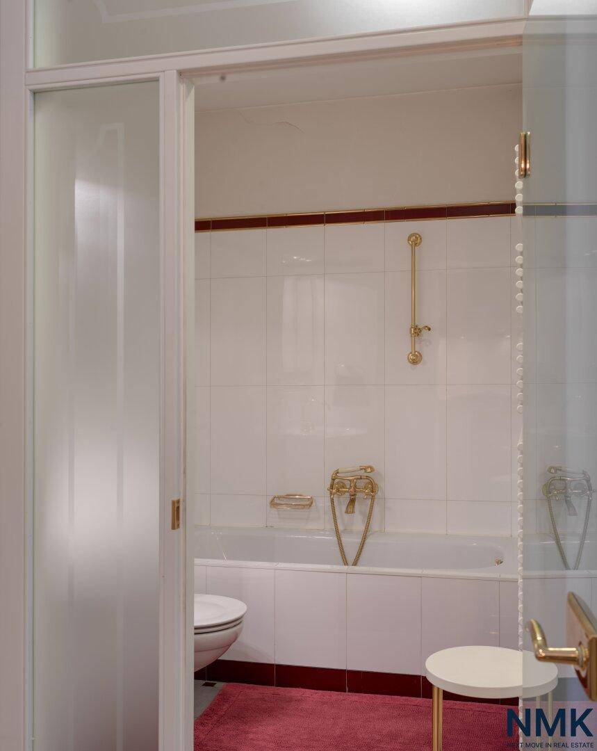 Klassisches Badezimmer mit Badewanne, Toilette und goldenen Armaturen.