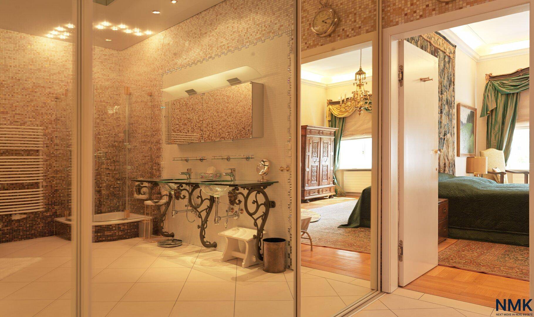 Großes Badezimmer mit Doppelwaschbecken, Dusche und Zugang zum Schlafzimmer.
