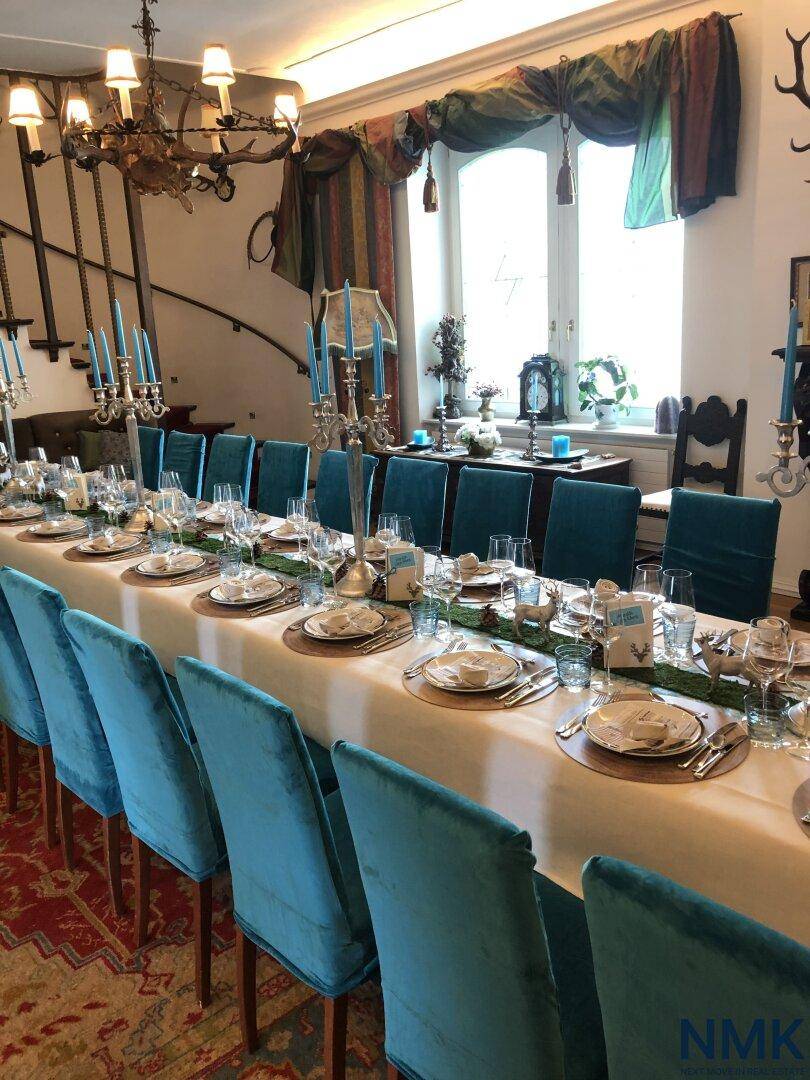 Festlich gedeckter Esstisch mit blauen Stühlen und Kronleuchter in einem eleganten Speisesaal.