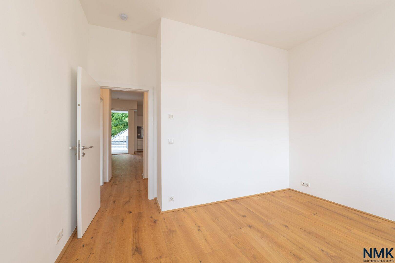 Helles Zimmer mit Holzboden und Zugang zu einem weiteren Bereich der Wohnung.