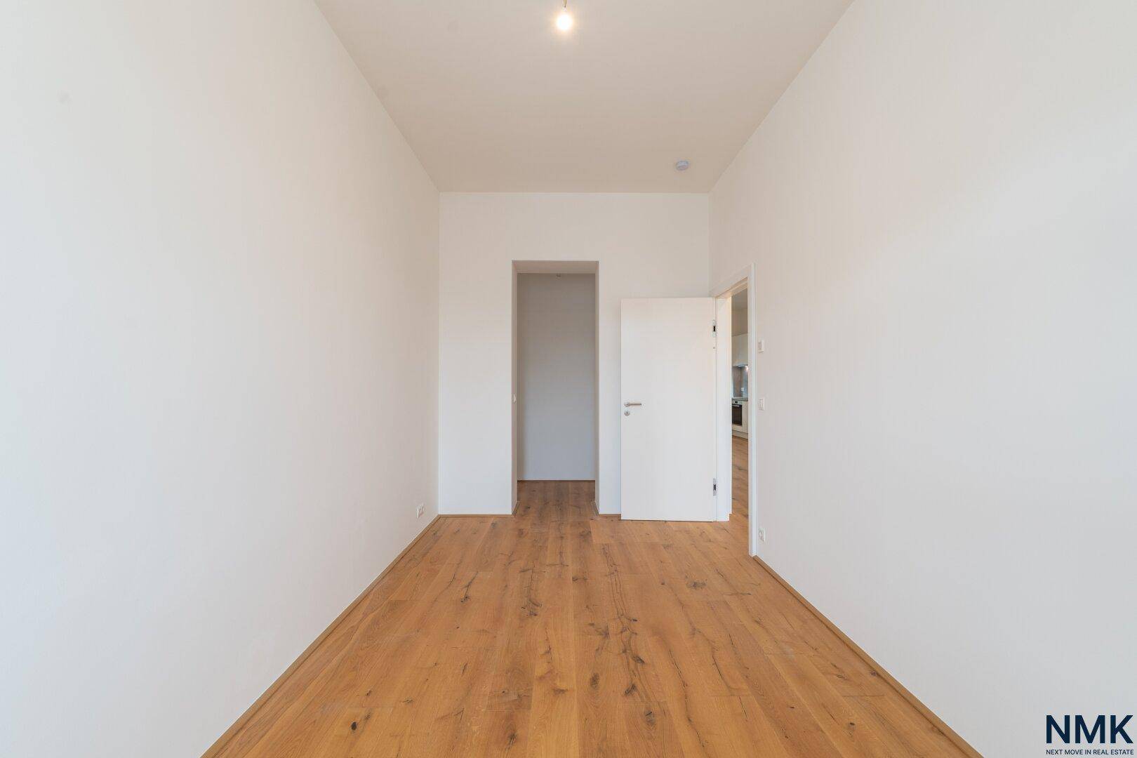 Schmaleres Zimmer mit Holzboden und Zugang zu anderen Räumen der Wohnung.