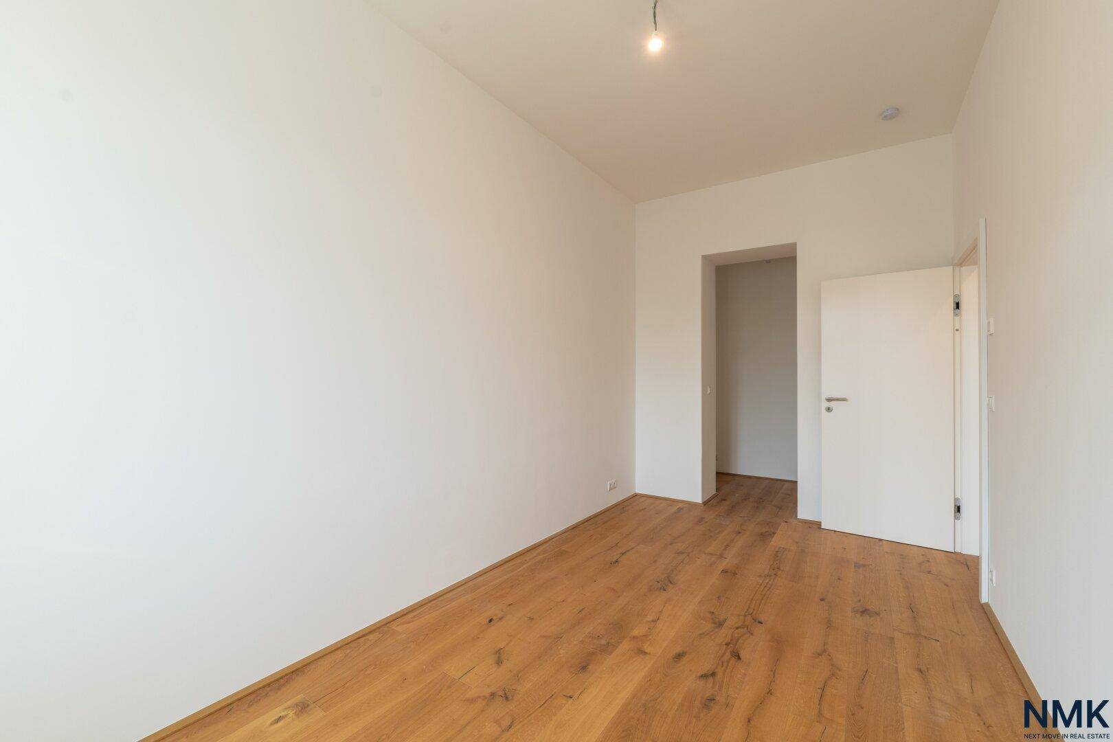 Helles Zimmer mit Holzboden und weiß gestrichenen Wänden, bereit zum Einzug.