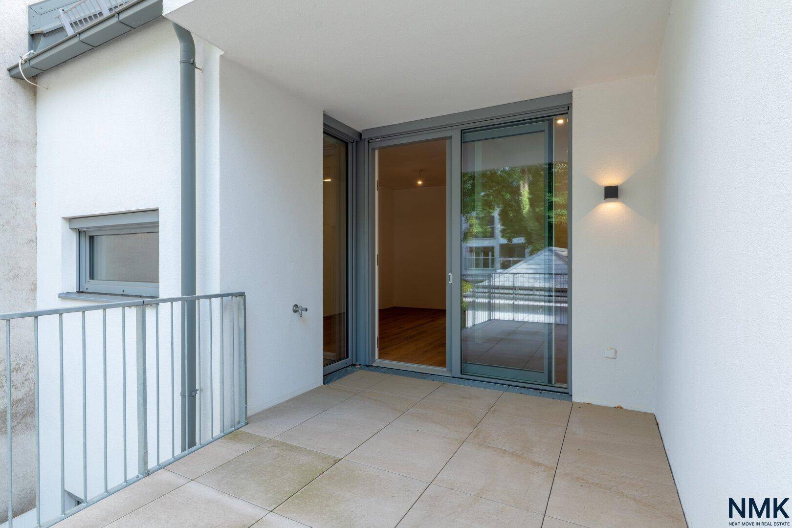 Balkon mit Fliesenboden und Zugang durch große Schiebetüren zum Innenbereich der Wohnung.