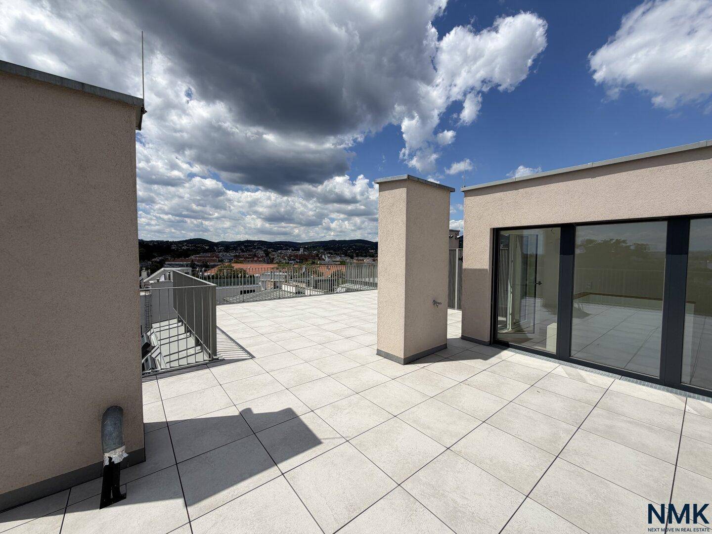 Weitläufige, unmöblierte Dachterrasse mit Fliesenboden und Blick auf die Umgebung.