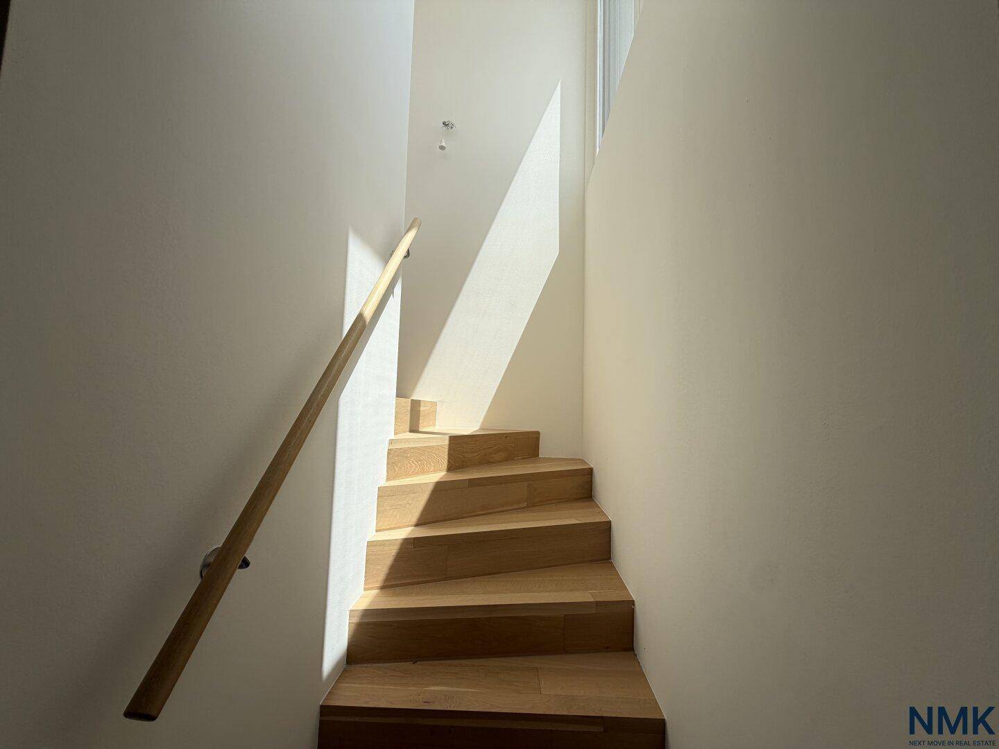 Helle Holztreppe mit natürlichem Lichteinfall und schlichtem Geländer.