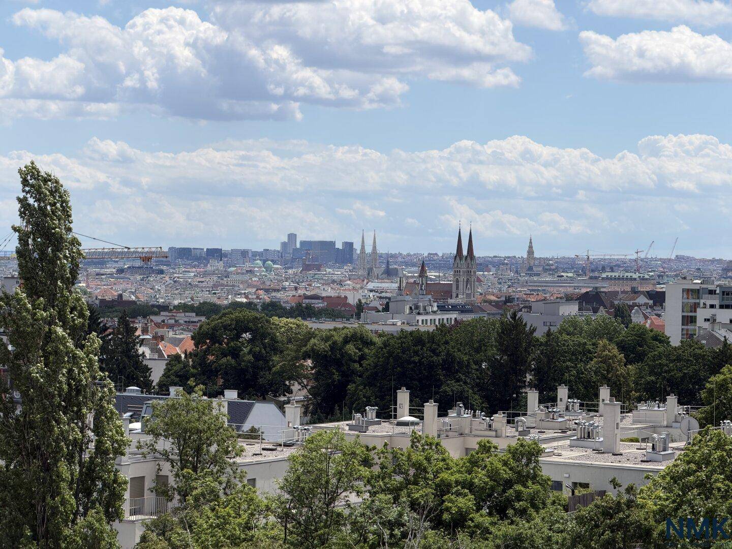 Panoramablick über die Stadt mit historischen Gebäuden und grünen Baumkronen.