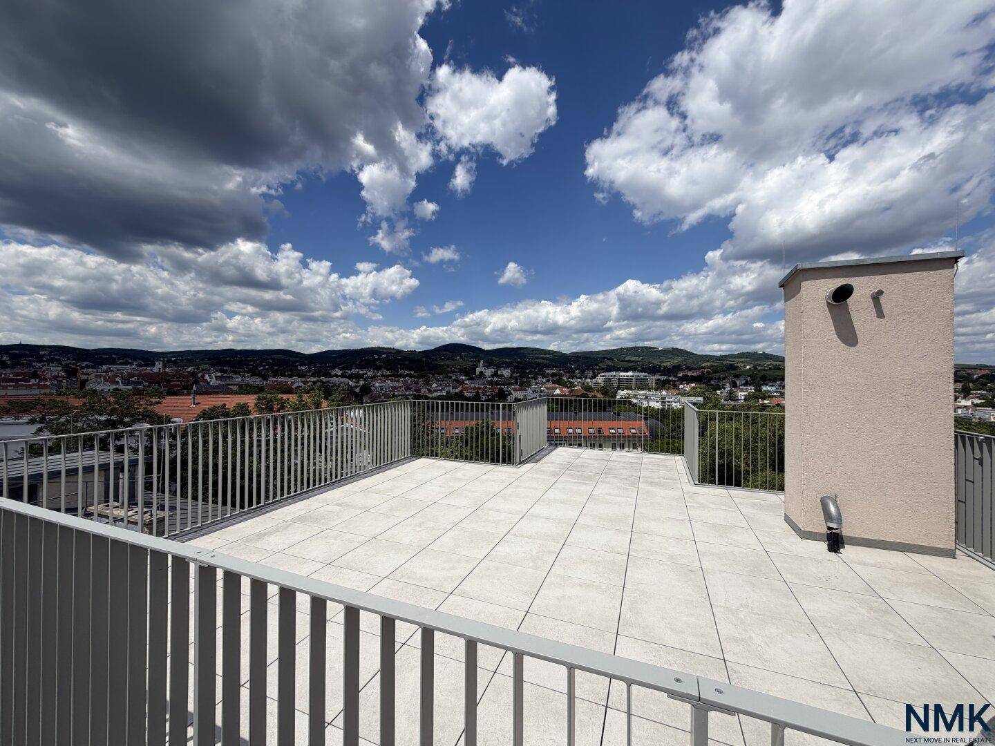Geräumige, unmöblierte Dachterrasse mit Fliesenboden und weitem Blick auf die Stadt.