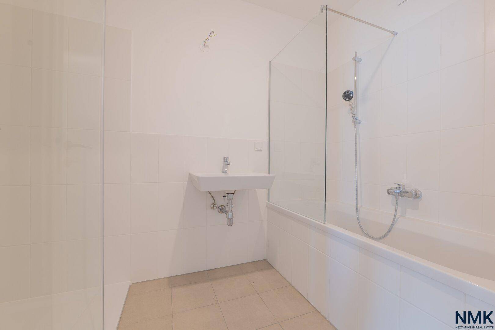 Modernes Badezimmer mit Badewanne, Glasabtrennung und einem einzelnen Waschbecken.