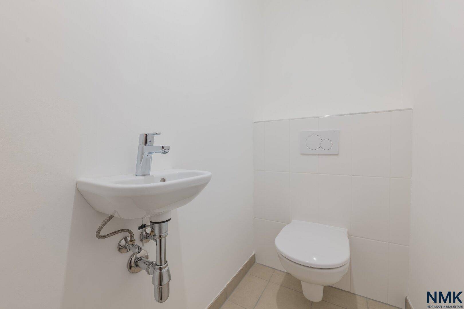 Modernes Gäste-WC mit wandhängender Toilette und kleinem Waschbecken in schlichtem Design.