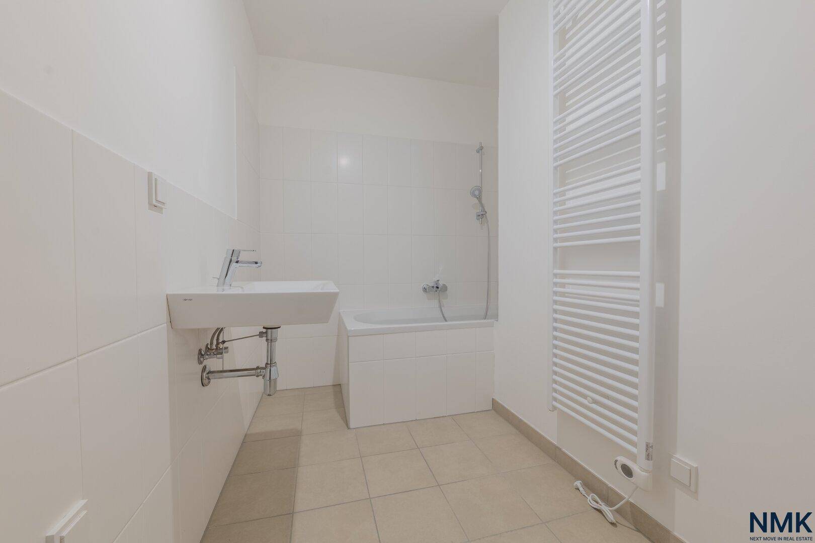 Helles Badezimmer mit Badewanne, Waschbecken und praktischem Handtuchheizkörper.