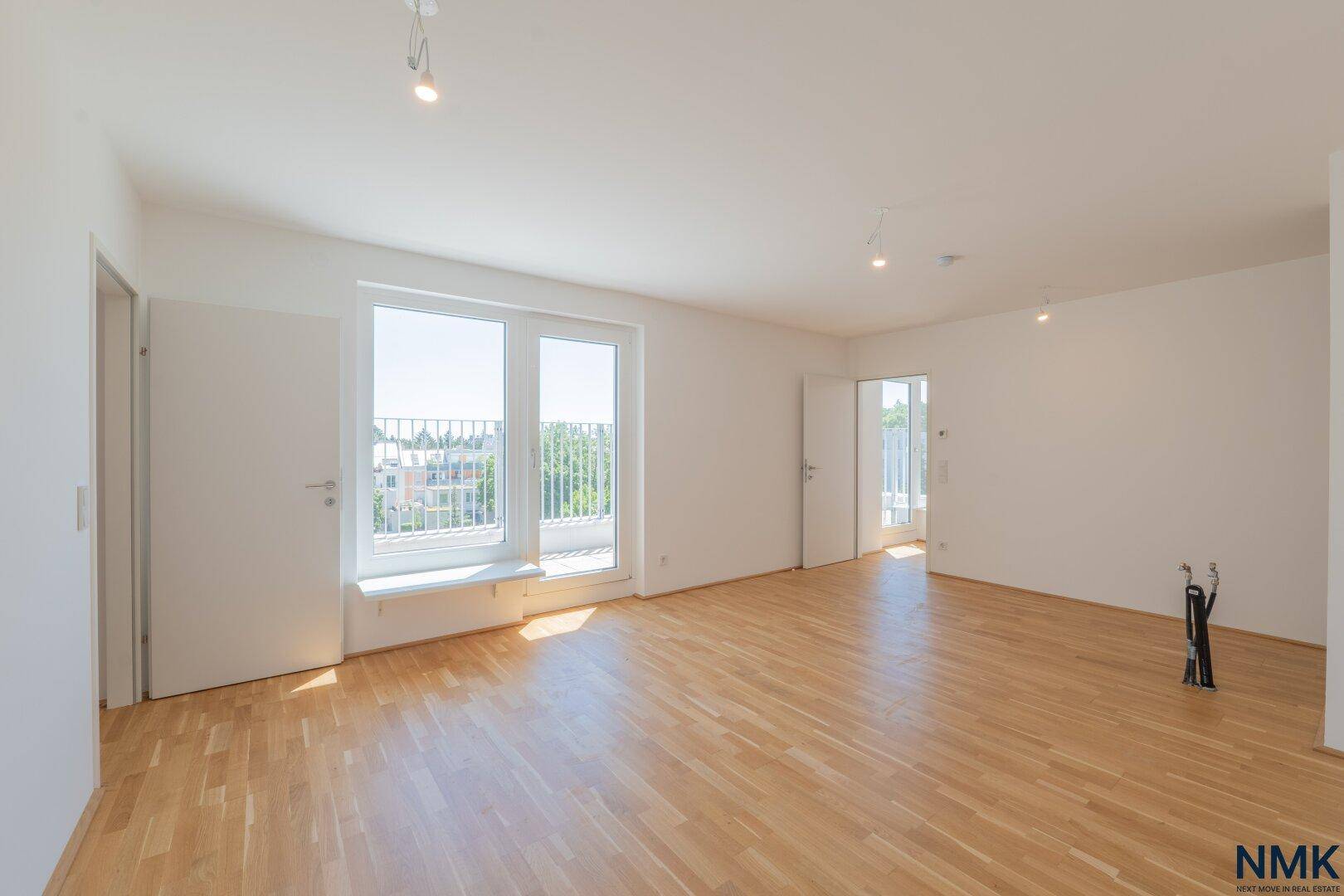 Geräumiger, heller Wohnbereich mit Parkettboden und Zugang zu einem Balkon.