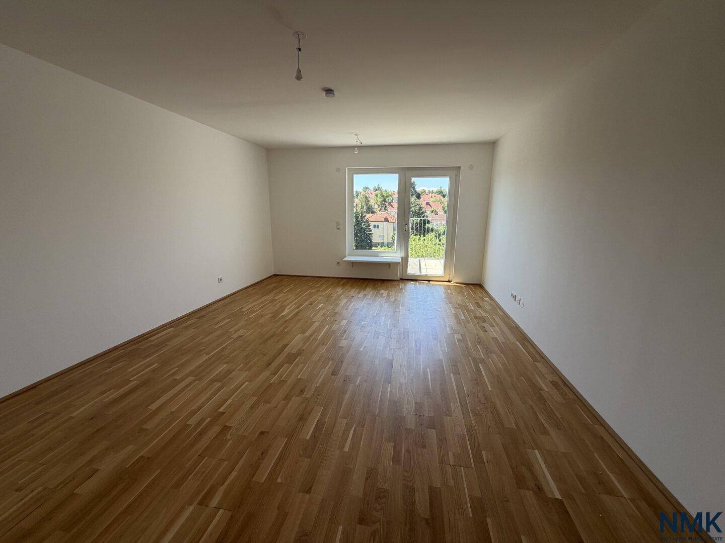 Heller Wohnraum mit Eichenparkett und Zugang zu einem Außenbereich, ideal für viel Tageslicht.