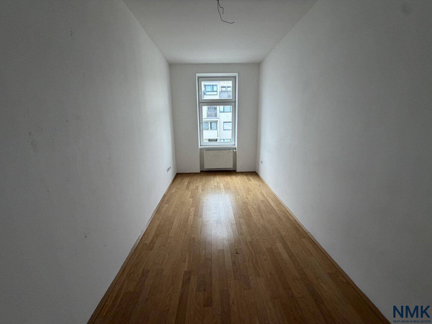 Leeres Schlafzimmer mit Holzparkettboden und Fenster, bereit für die individuelle Einrichtung.