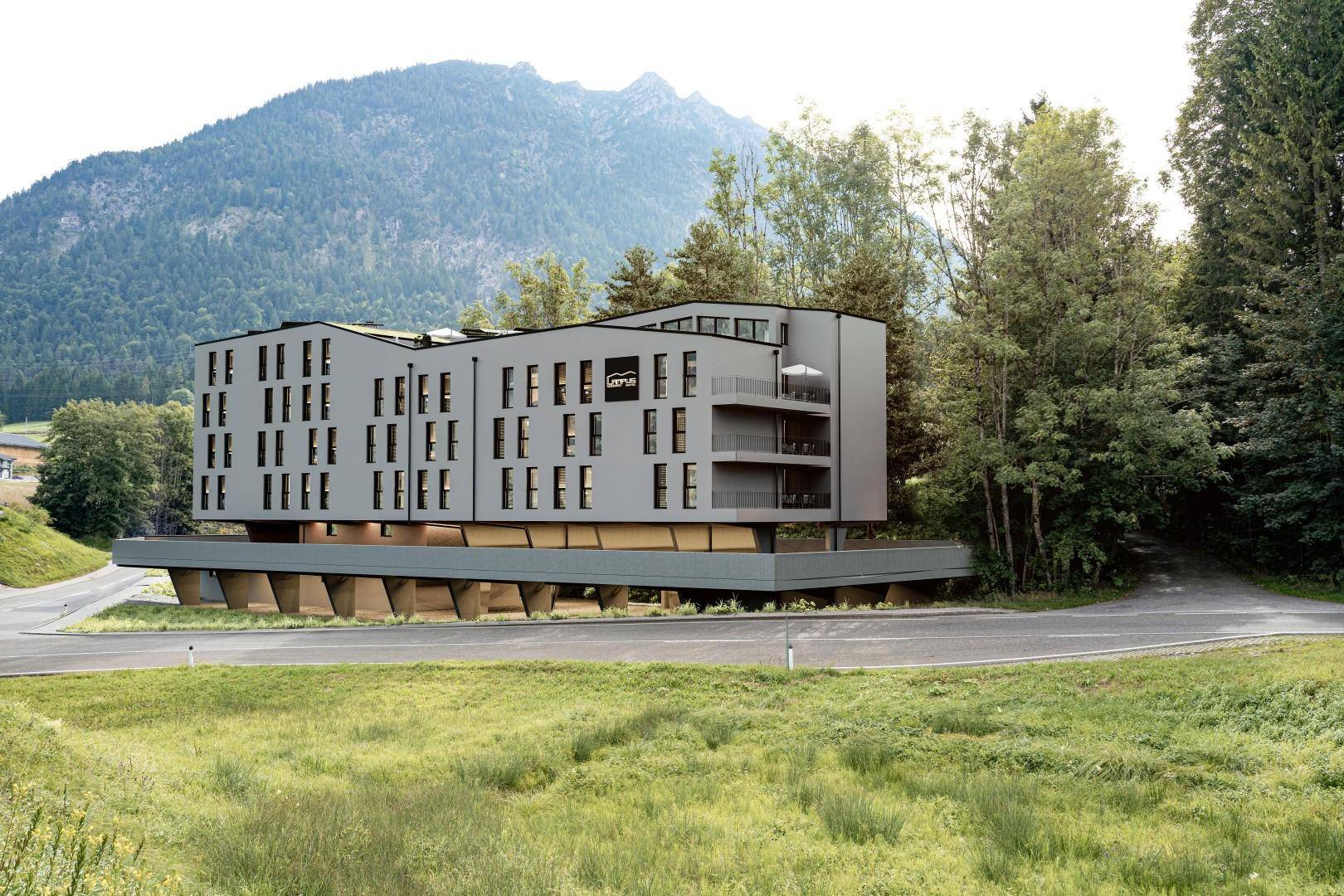 Modernes Gebäude mit klarer Architektur und Balkonen, eingebettet in eine grüne Berglandschaft.