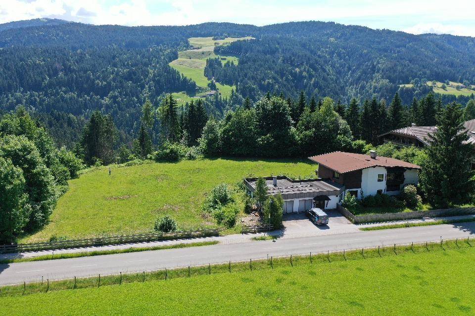 Luftaufnahme eines Hauses mit großem Grundstück, umgeben von Wäldern und Bergen.