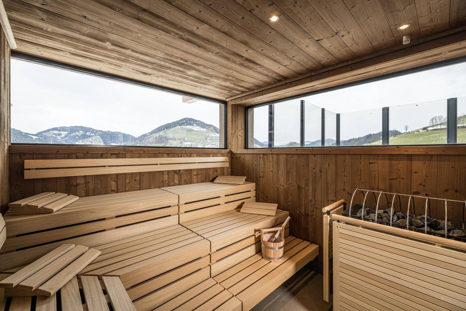 Geräumige Sauna mit Holzbänken und Panoramablick auf die umliegende Berglandschaft.