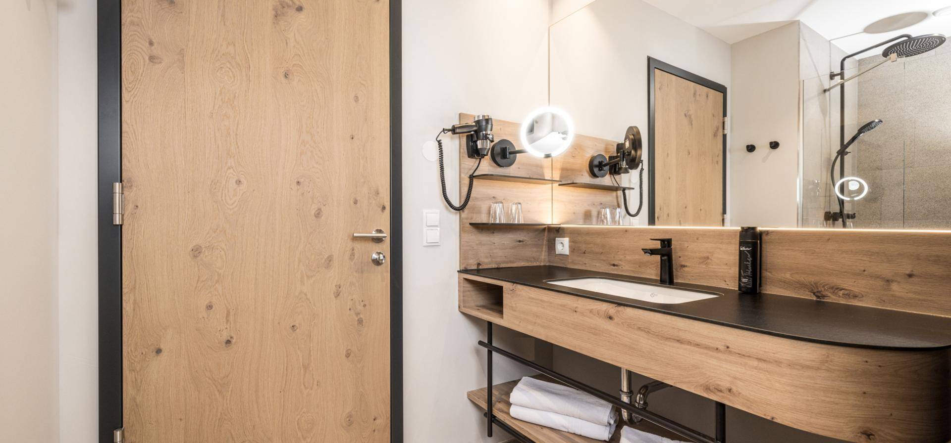 Modernes Badezimmer mit Holzwaschtisch, integriertem Waschbecken und großem Spiegel.