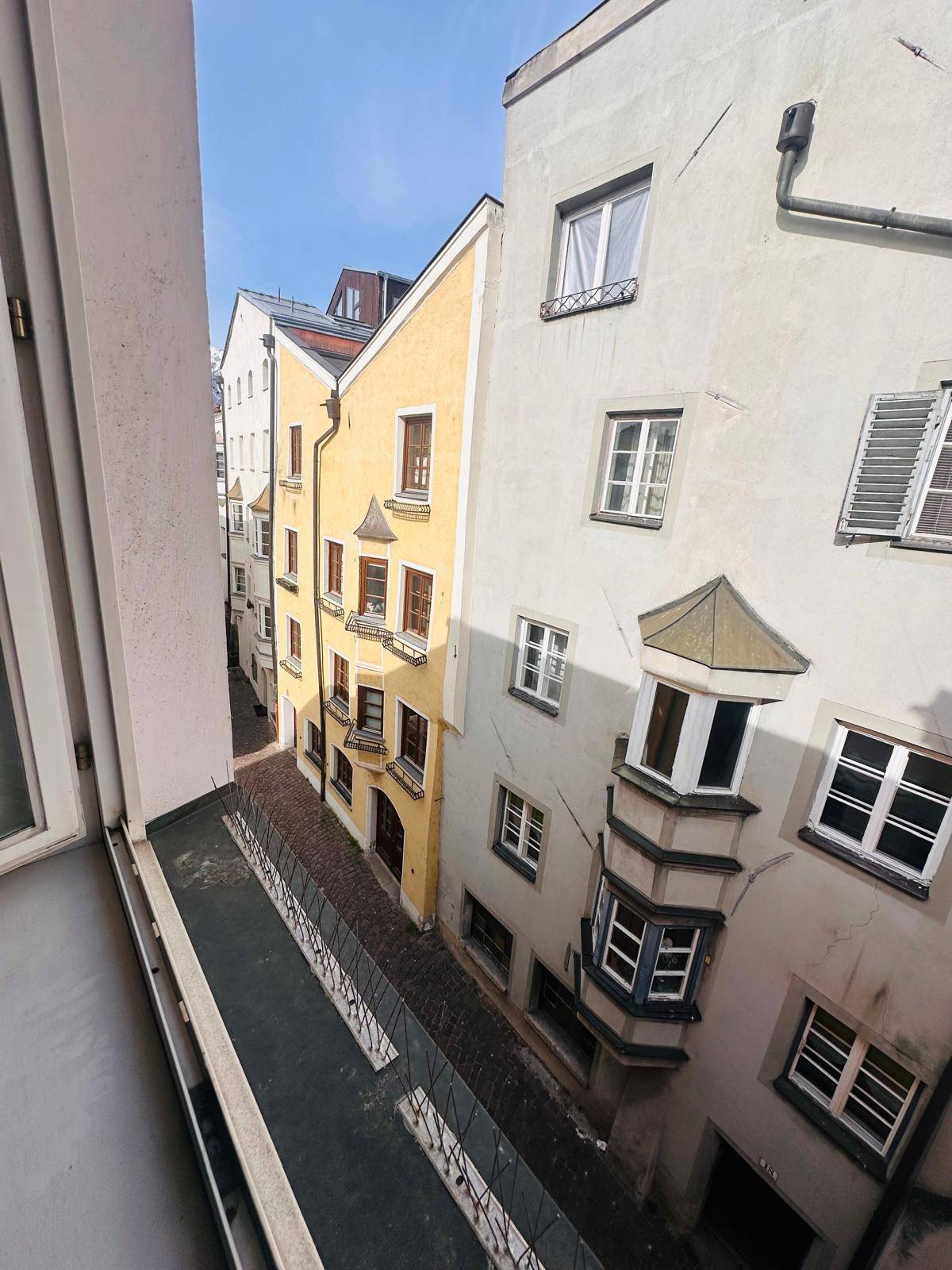 Blick aus dem Fenster in eine enge Gasse mit historischen Gebäuden und traditionellen Erkern.