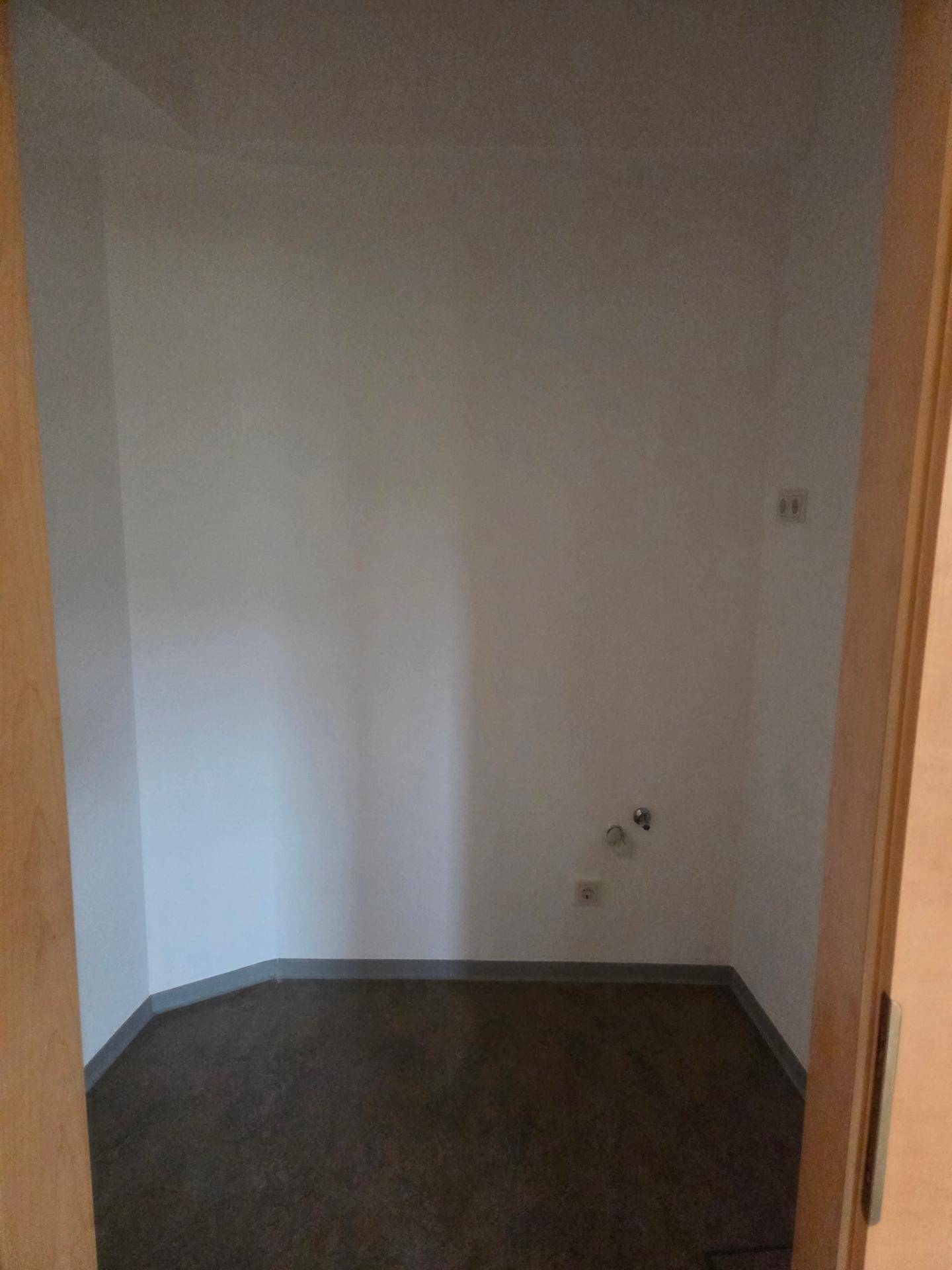 Kleiner Abstellraum oder Technikraum mit dunklem Boden und Steckdosen an der Wand.