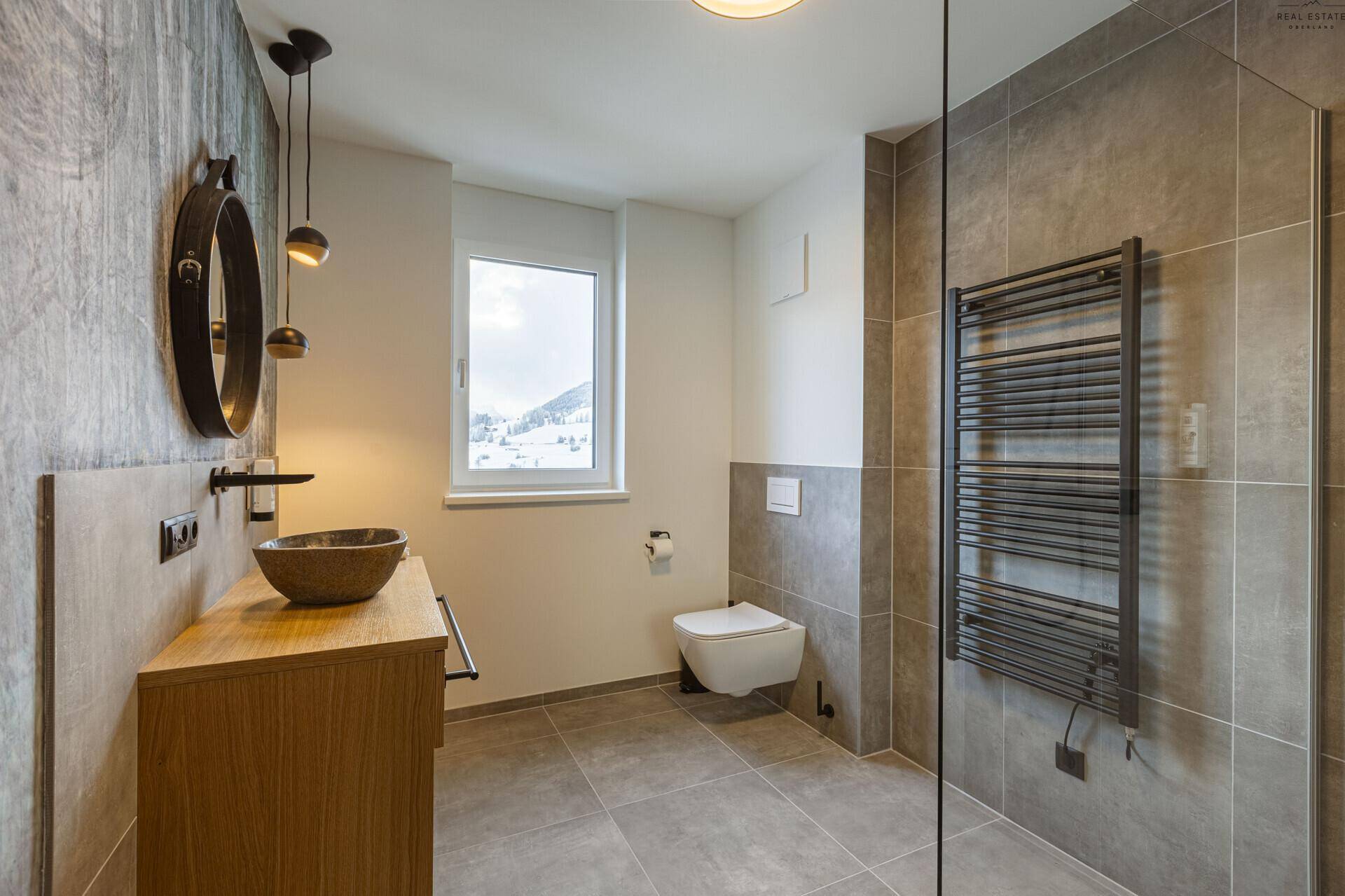 Modernes Badezimmer mit begehbarer Dusche, Einzelwaschbecken und beheiztem Handtuchhalter.