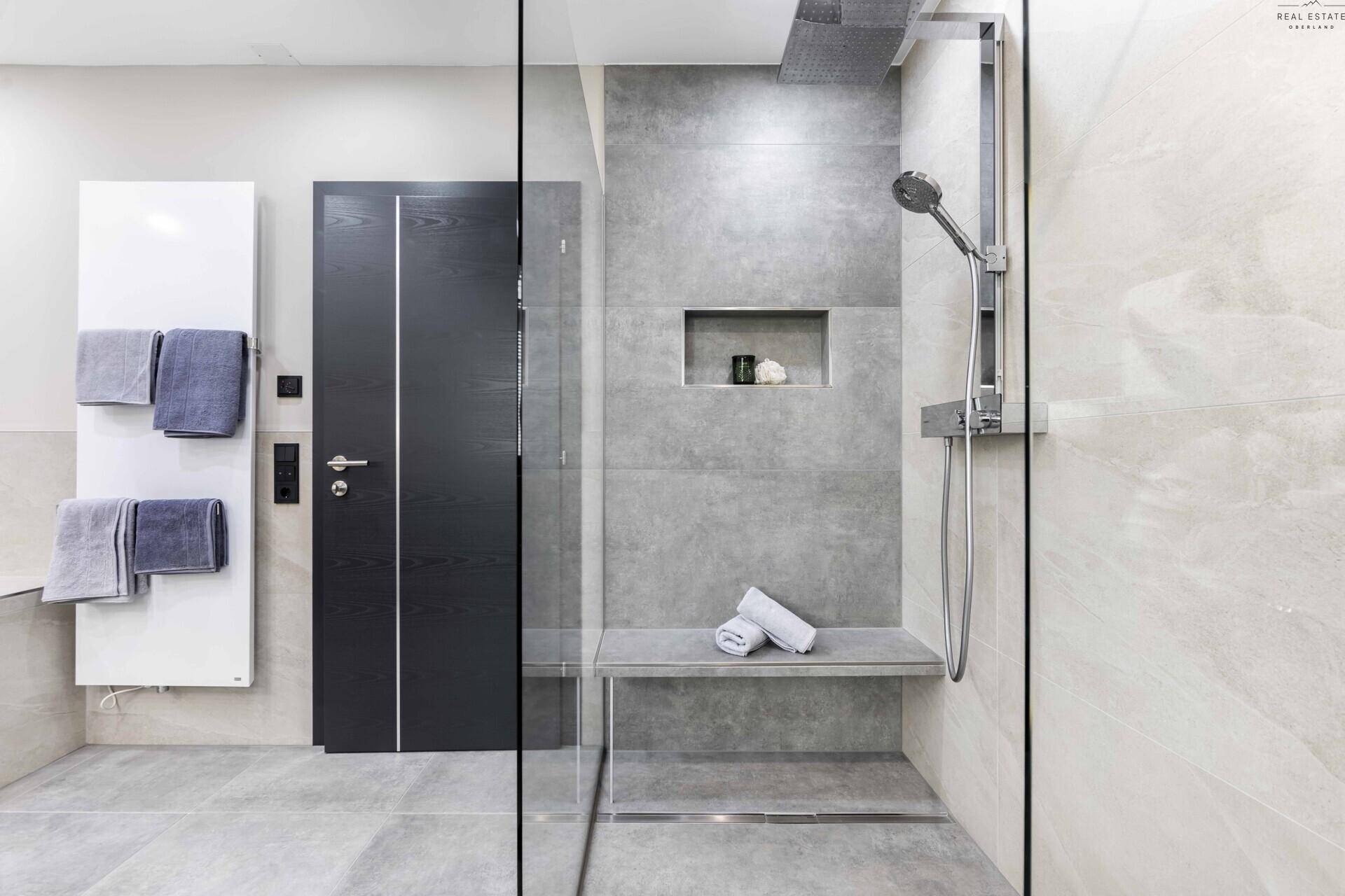 Großzügige begehbare Dusche mit Sitzbank und moderner Regendusche im eleganten Badezimmer.
