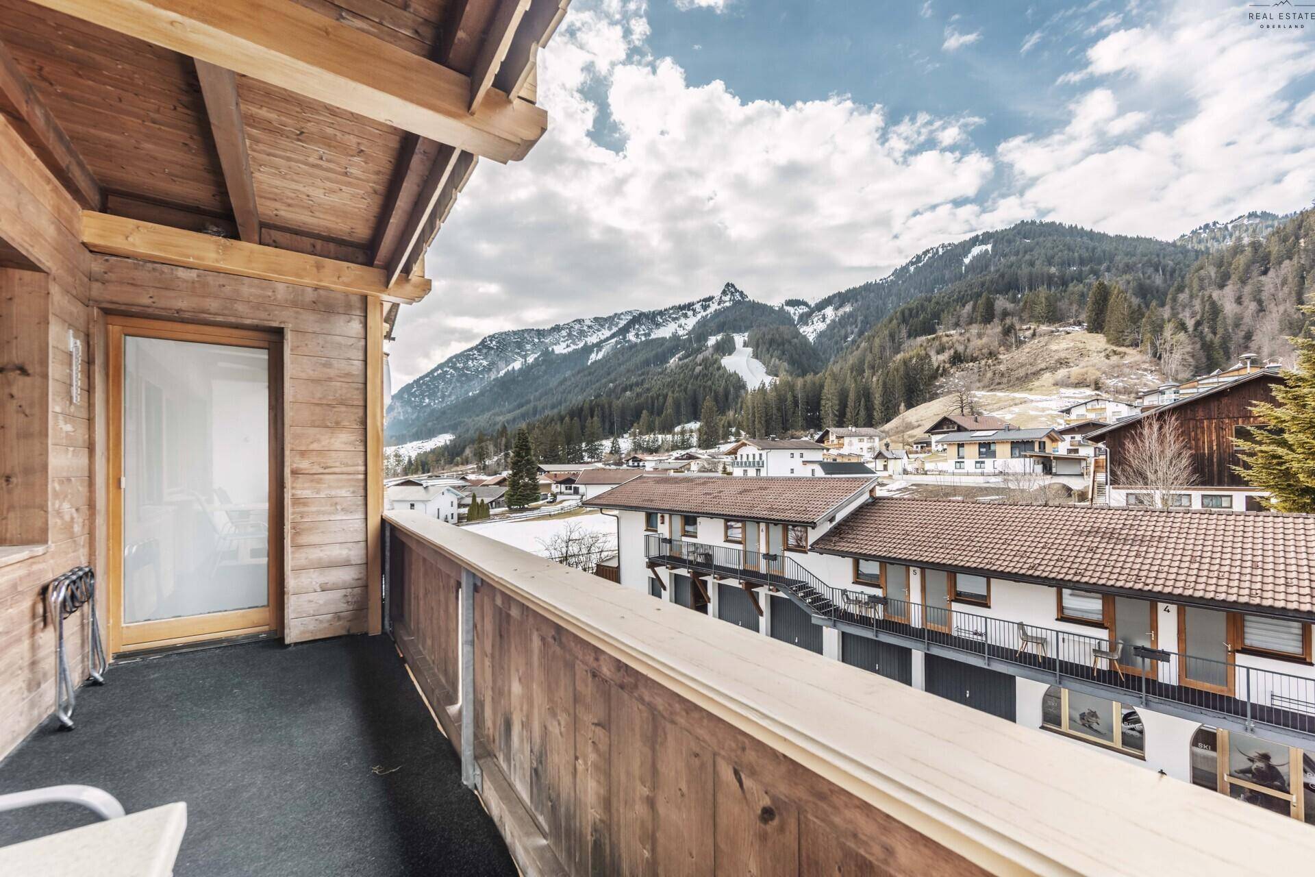 Balkon mit Holzboden und Geländer, bietet einen Panoramablick auf die Berglandschaft.