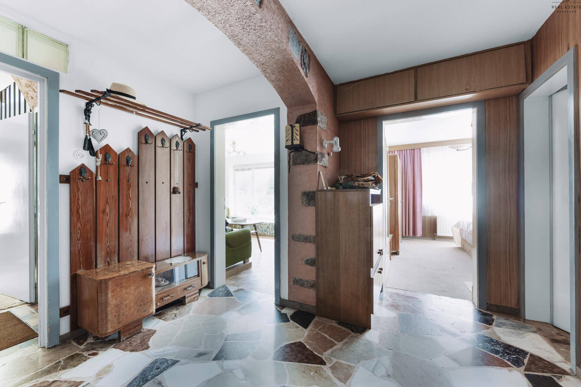 Eingangsbereich mit Terrazzoboden, Holzvertäfelung und rustikaler Garderobe.