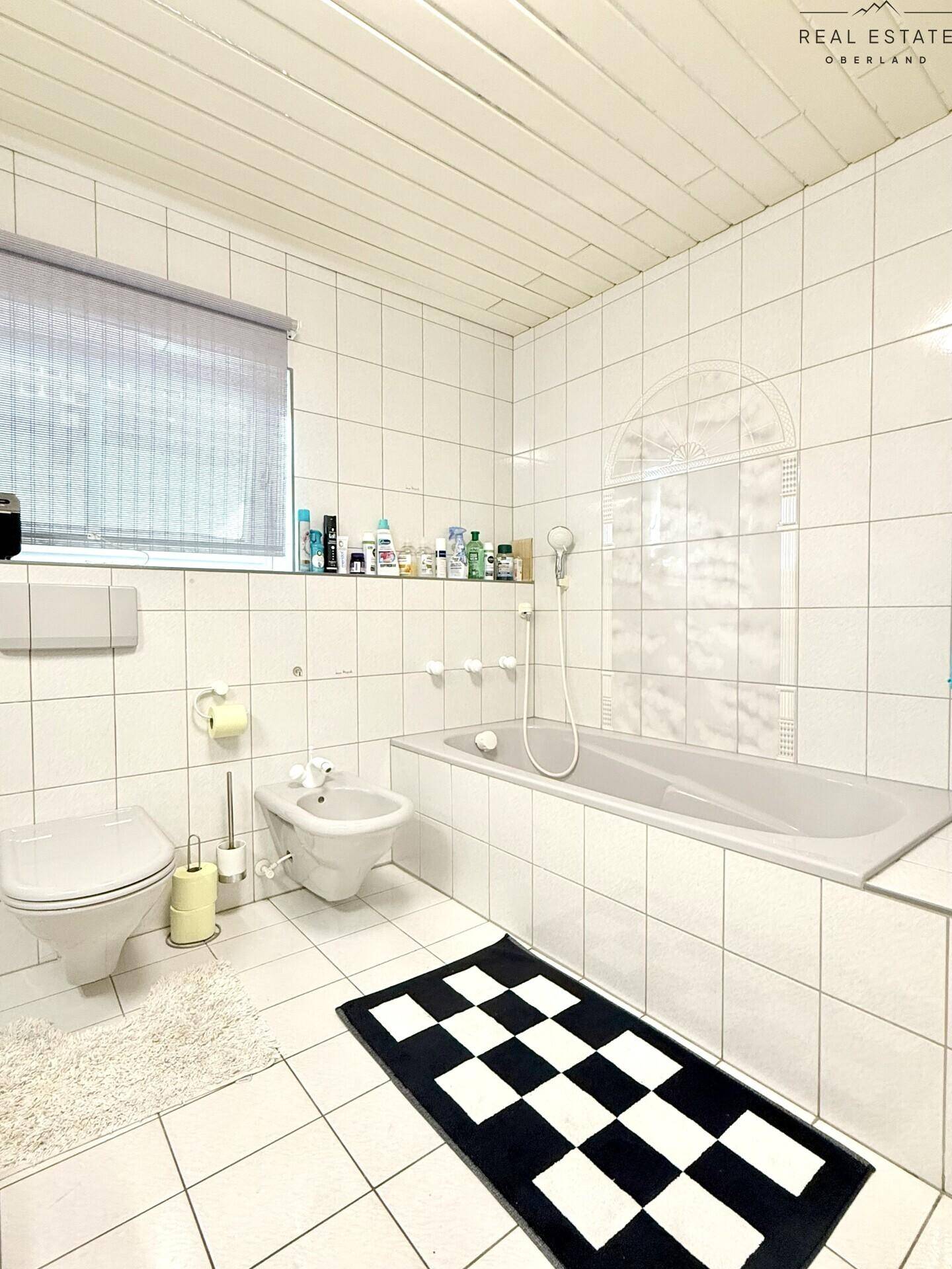 Badezimmer mit Badewanne, Bidet, WC und weißen Fliesen.