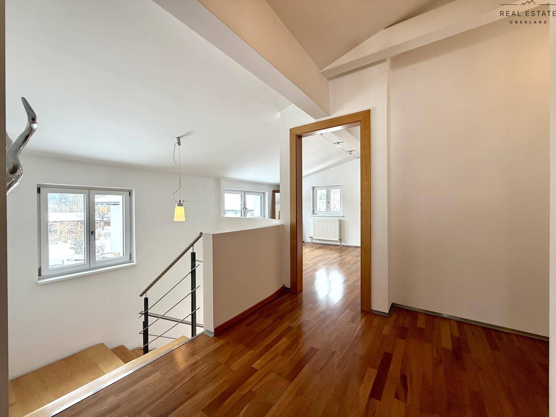 Heller Flurbereich mit Holzfußboden, Treppe und Fenstern, die für natürliches Licht sorgen.