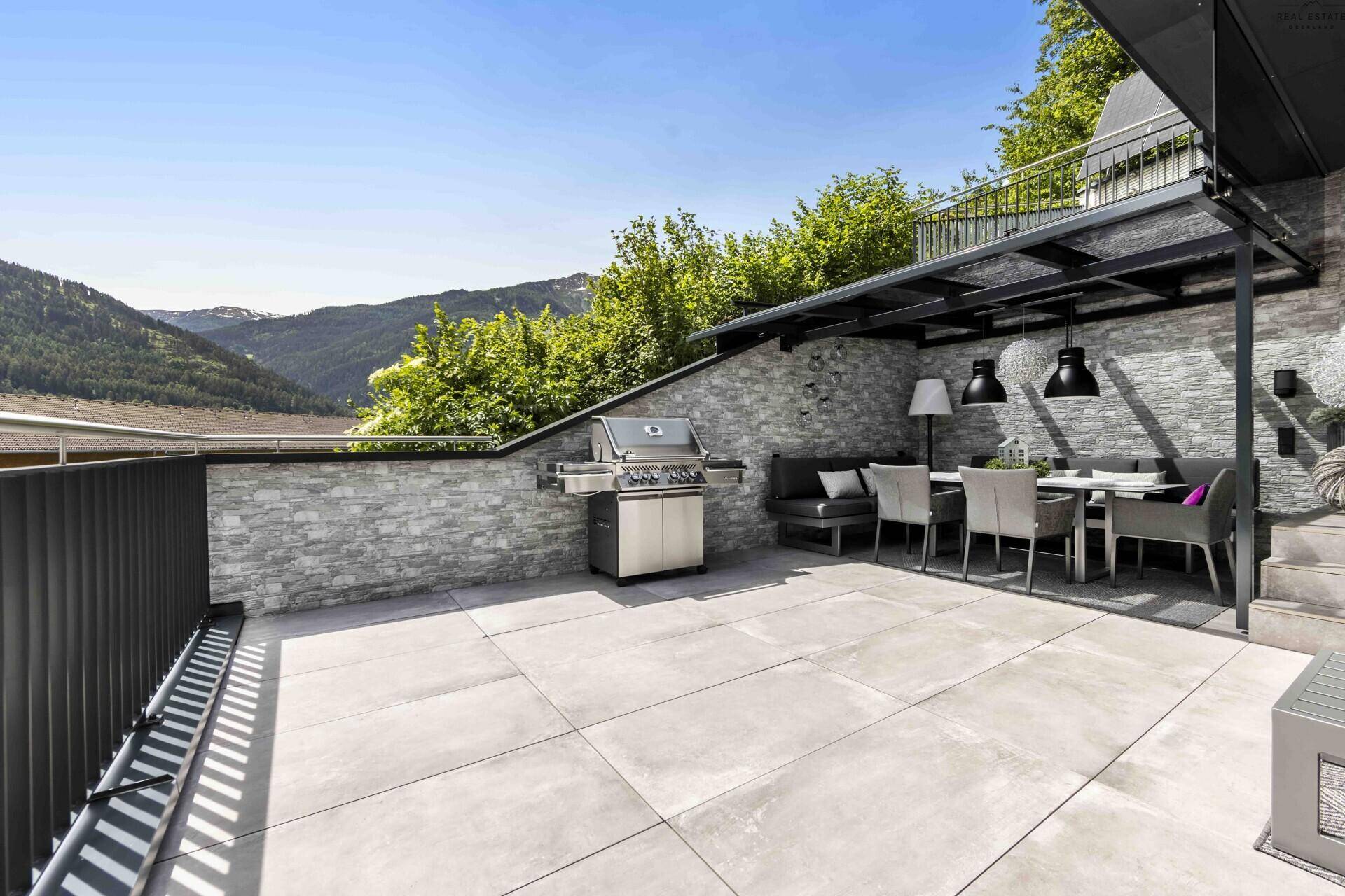 Geräumige Terrasse mit Grillstation und Essbereich, ideal für Mahlzeiten im Freien mit Bergblick.