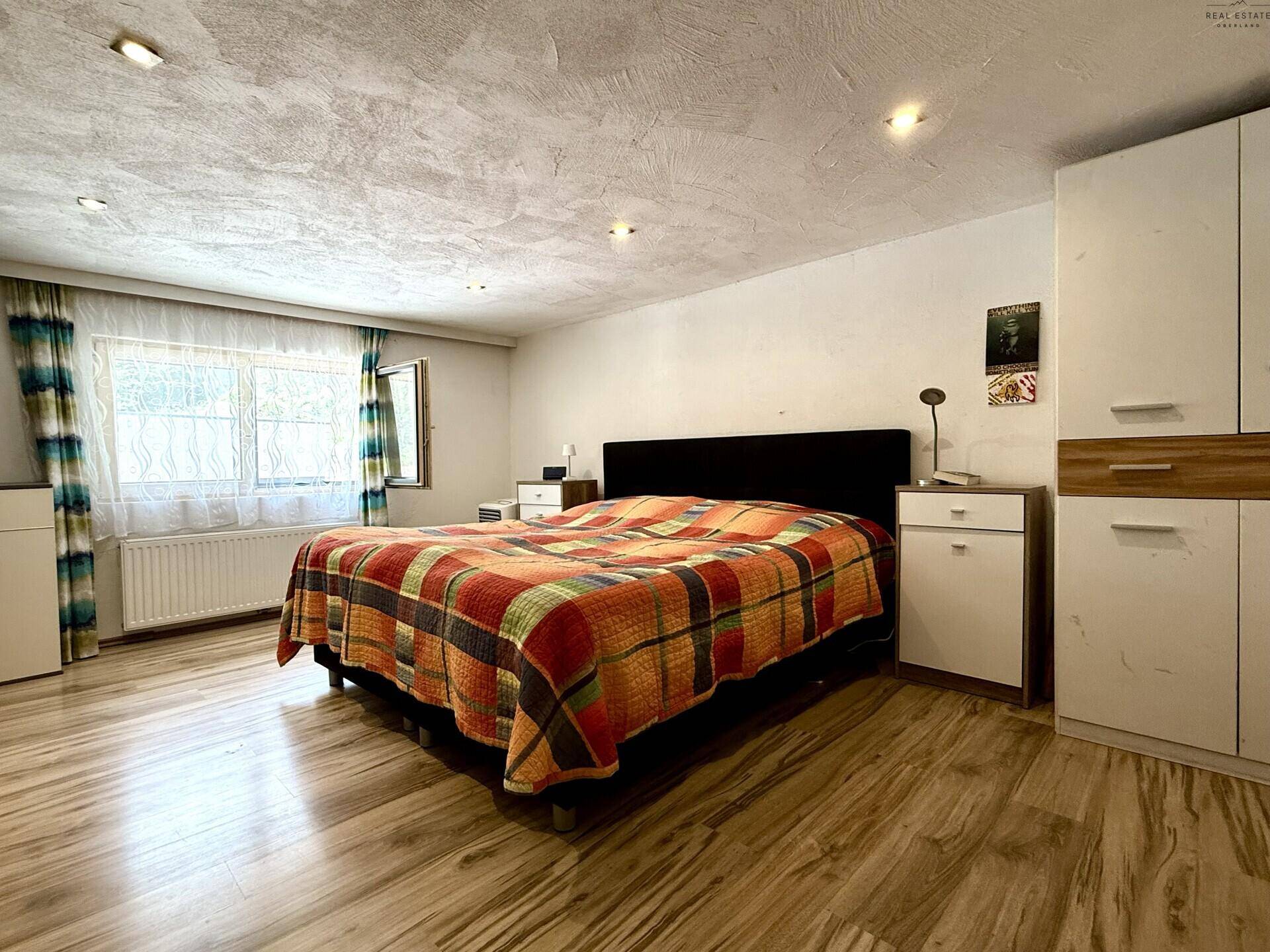 Geräumiges Schlafzimmer mit Doppelbett, Holzschrank und Fenster, bietet viel natürliches Licht.