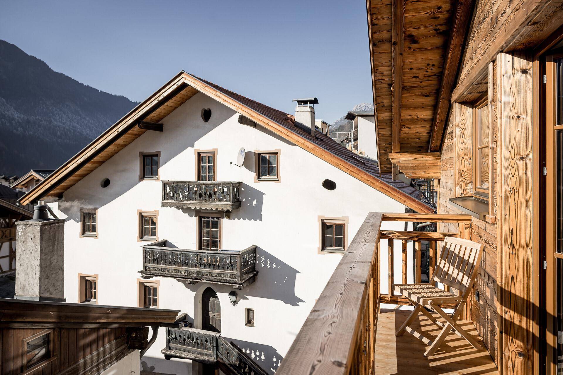 Traditionelles Gebäude mit Holzbalkonen und Blick auf die umliegende Berglandschaft.