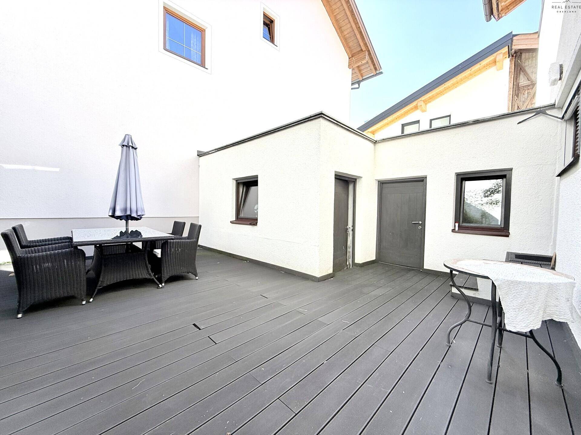 Große Terrasse mit dunklem Holzboden und Sitzgelegenheiten im Freien.