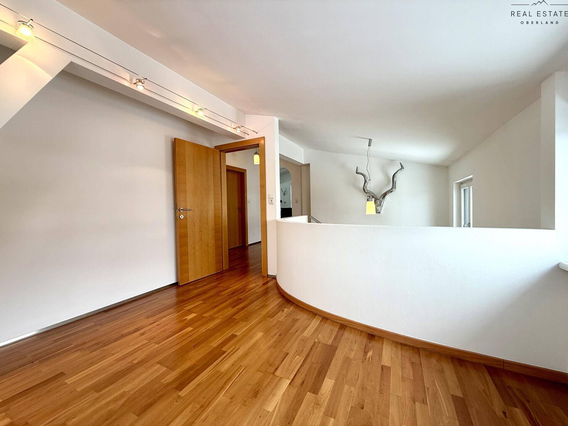Heller Flurbereich mit Holzfußboden und einem dekorativen Geweih an der Wand, führt zu weiteren Räumen.